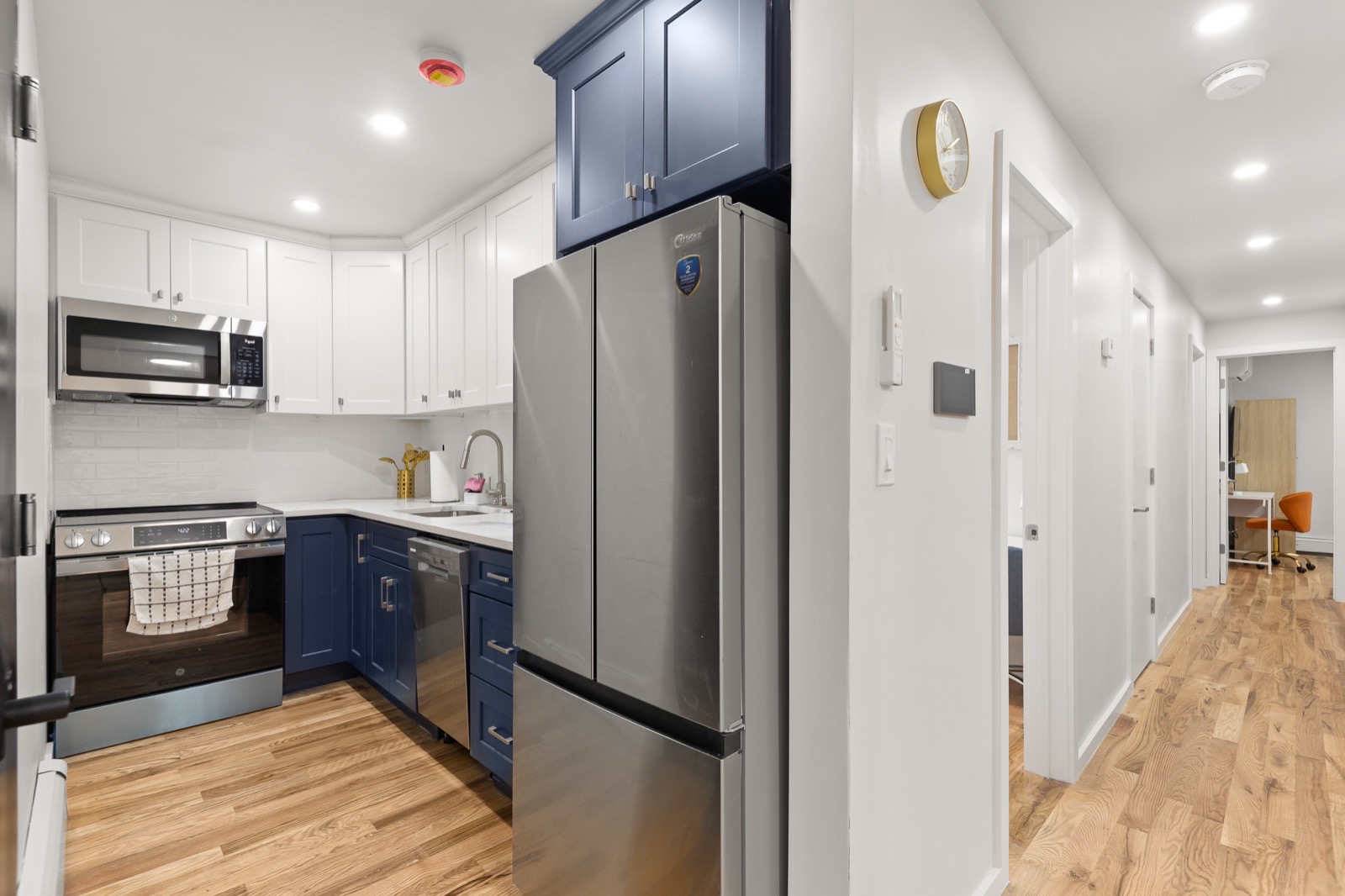 Equipped shared kitchen with stainless appliances and navy cabinets